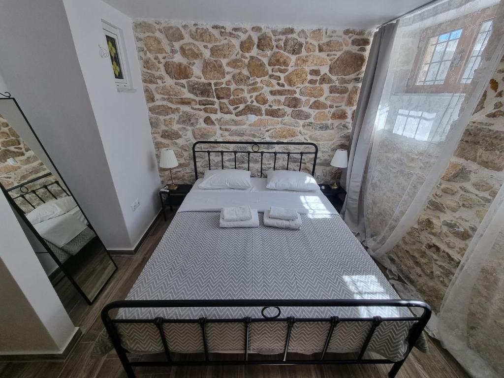 a bed in a room with a stone wall at Hall Apartments & Rooms - by Avelink in Spata