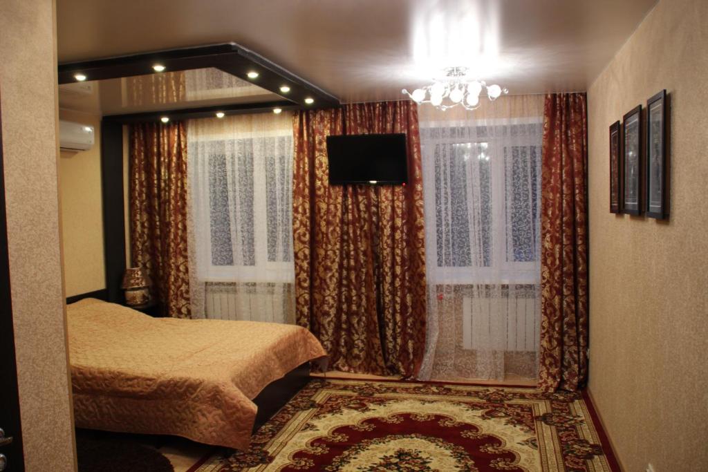 a bedroom with a bed and a window with a television at Hotel Lyuks in Arzamas