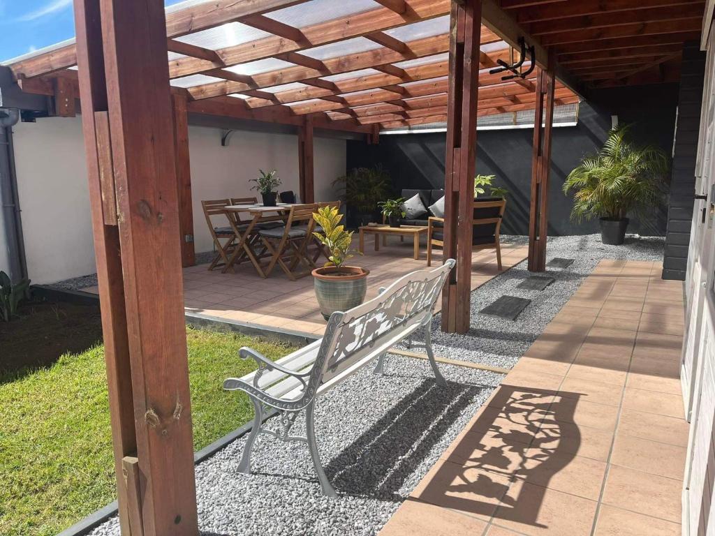 un banc sous une pergola en bois sur une terrasse dans l'établissement Vulkan’O, à Le Tampon