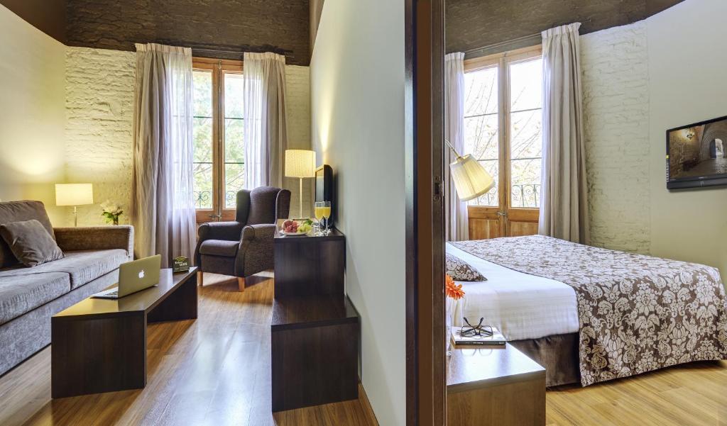 a hotel room with a bed, desk and a mirror at Hotel Rural y Apartamentos Villa Engracia in Espluga de Francolí