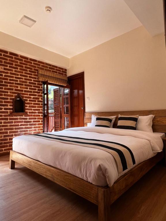 a bedroom with a large bed with a brick wall at KGH Patan in Pātan