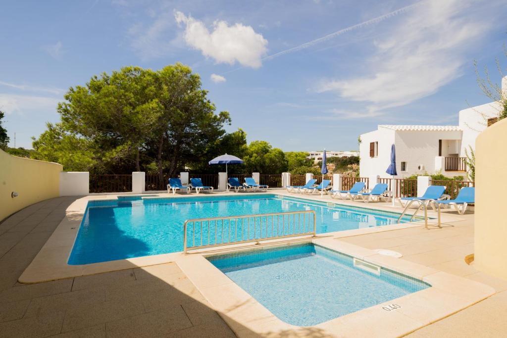 a swimming pool with blue lounge chairs and a swimming pool at Apartamentos Sa Cornisa in Cala Morell