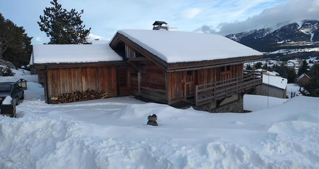 un chien assis dans la neige devant une cabine dans l'établissement Bolquère I Chalet Boolly 5 étoiles luxe et bois I Vue montagne, à Bolquère-Pyrénées 2000
