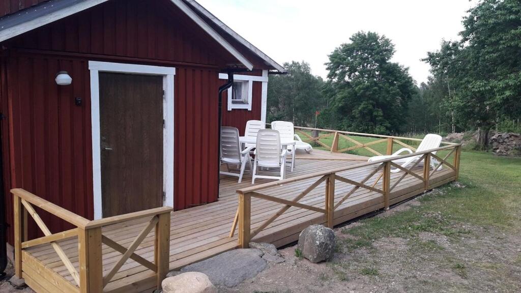 a wooden deck with chairs and a red building at Stuga Sörgarden in Åsenhöga