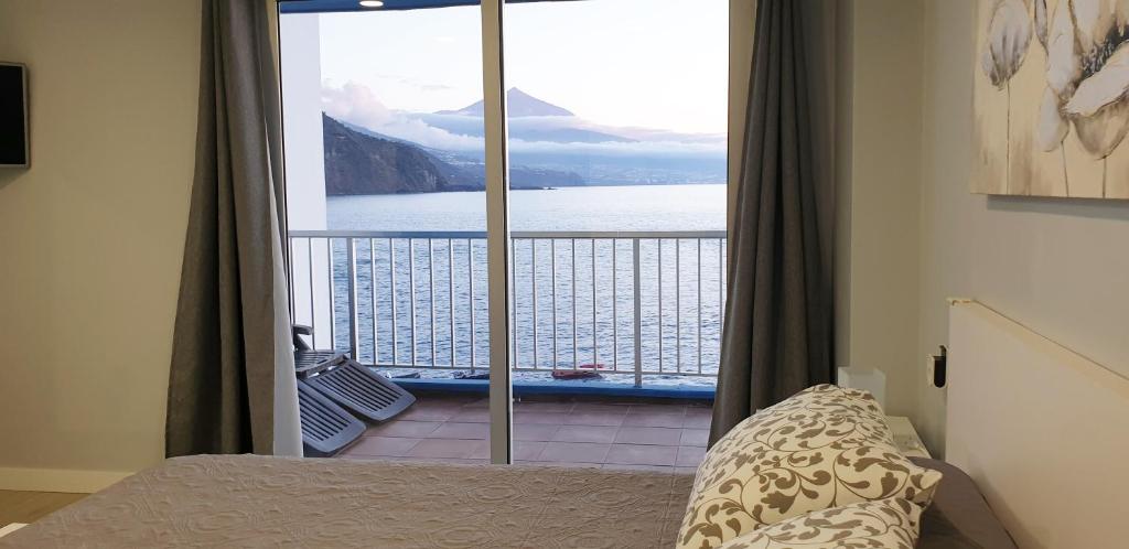a bedroom with a balcony with a view of the water at Crepúsculo in Puerto de la Madera