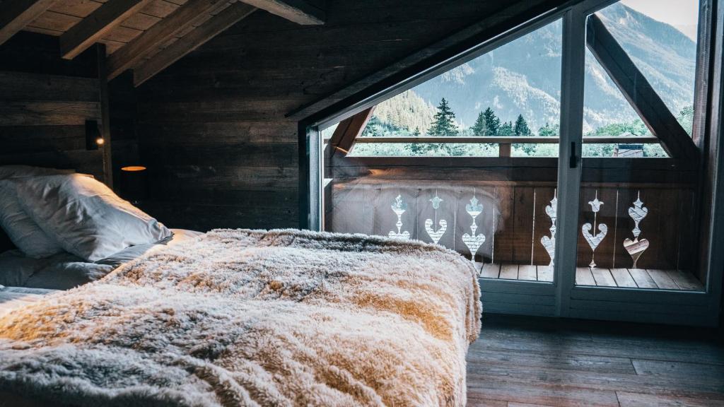 a bed in a room with a large window at Chalet Camillou in Champagny-en-Vanoise
