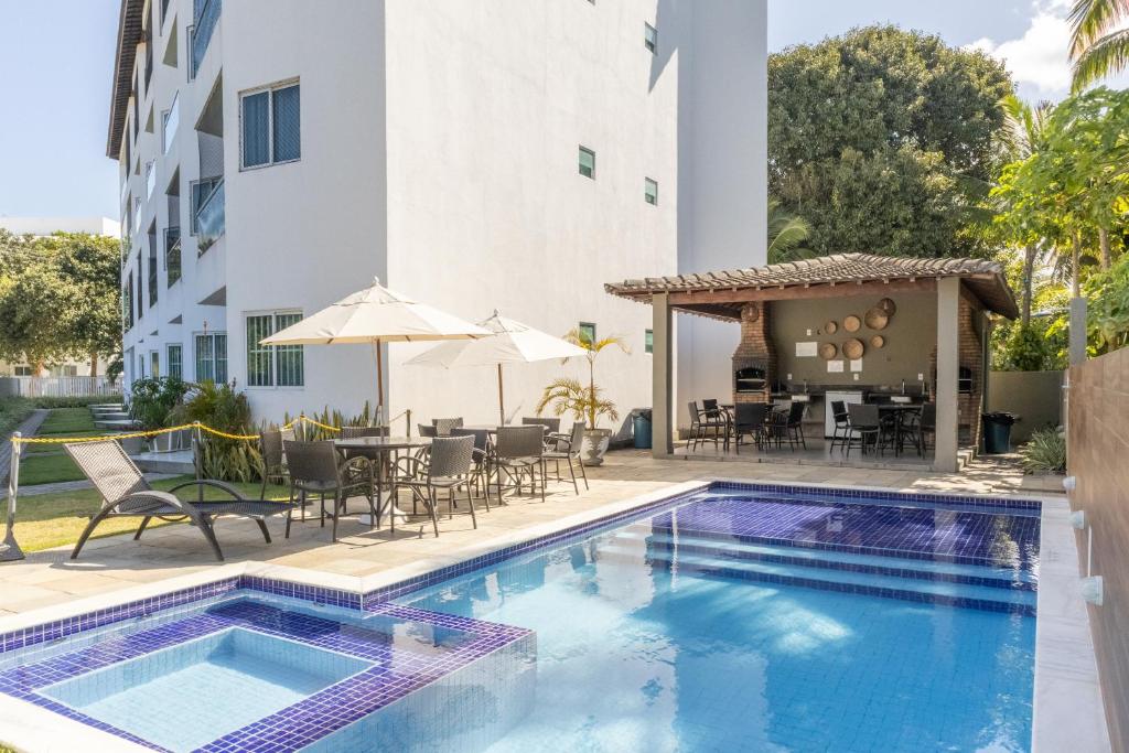 uma piscina com mesa e cadeiras ao lado de um edifício em Aquarius Residence em Porto de Galinhas