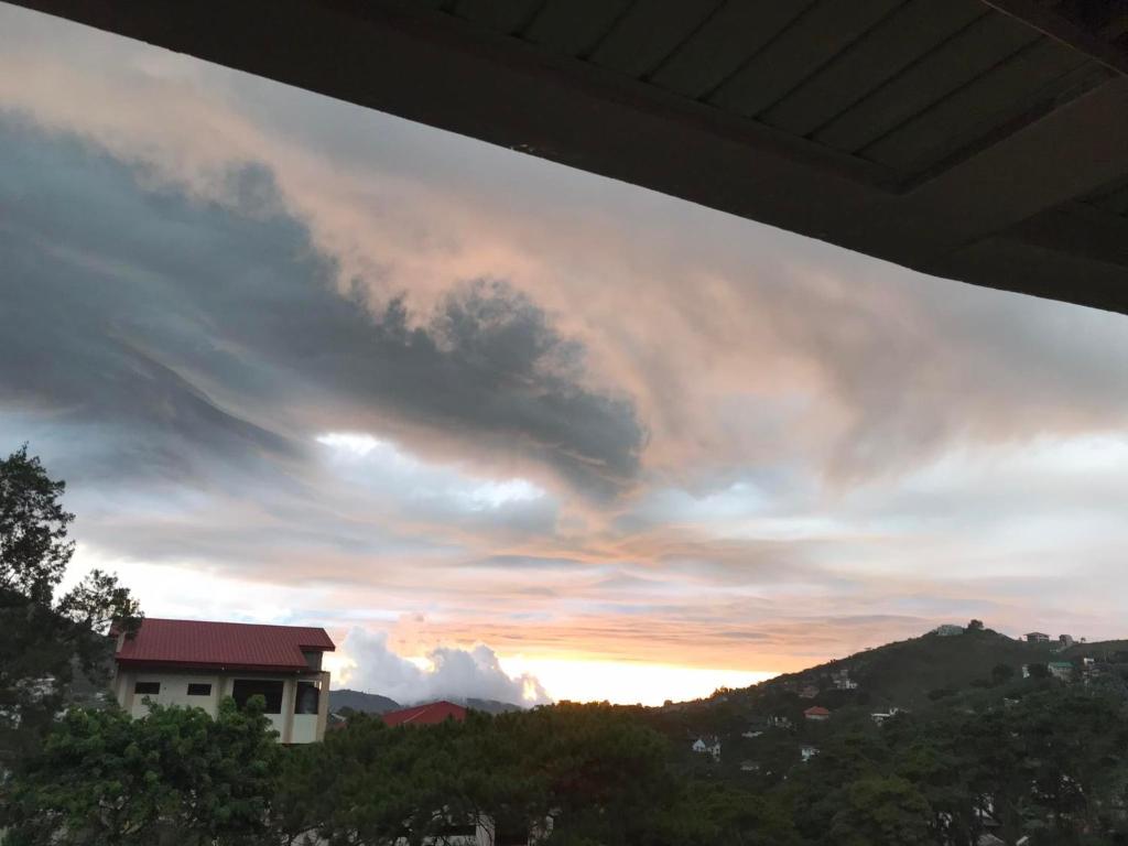 a cloudy sky at sunset with a house in the foreground at Moldex Residence in Baguio