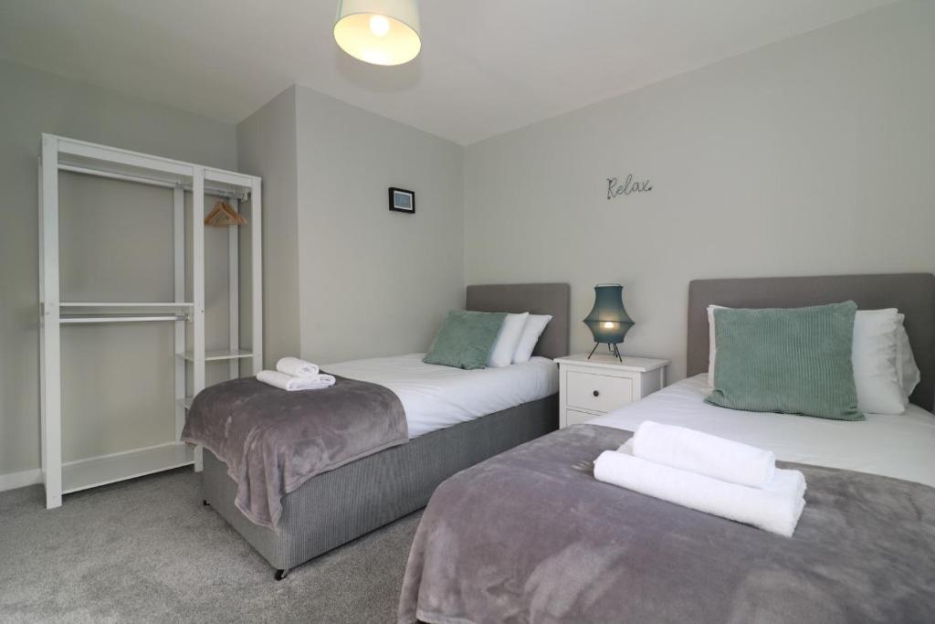a bedroom with two beds and a window at Signature - Sydney House in East Kilbride