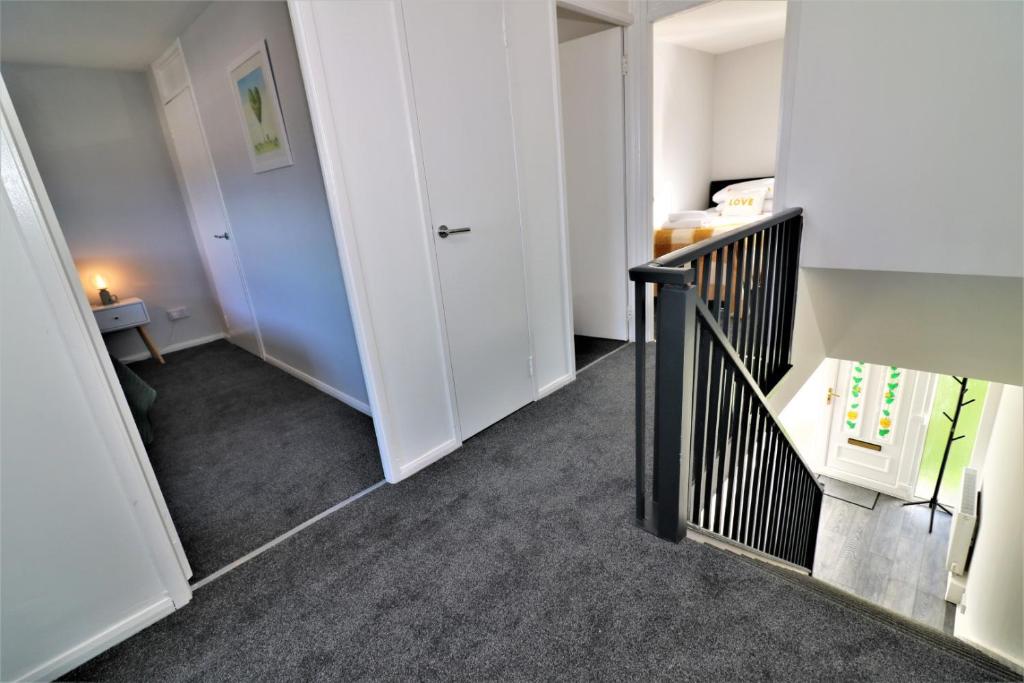 a hallway with a stairway with a white door at Signature - Morland House in East Kilbride