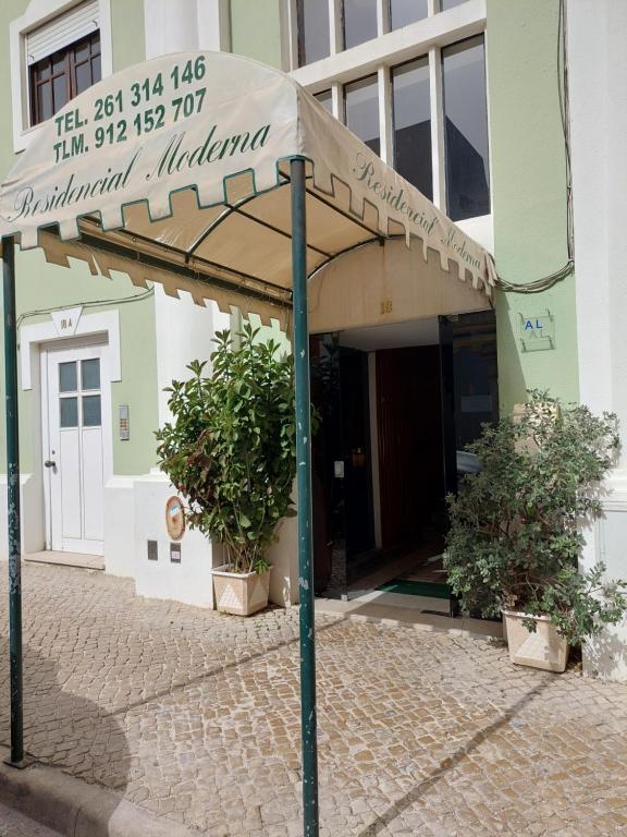 an umbrella on a sidewalk in front of a building at Residencial Moderna in Torres Vedras