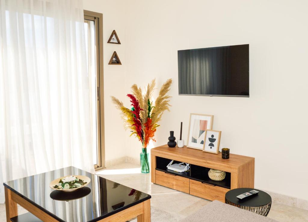 ein Wohnzimmer mit einem Tisch und einem TV an der Wand in der Unterkunft Appartement Cosy, vue sur mer in Mohammedia