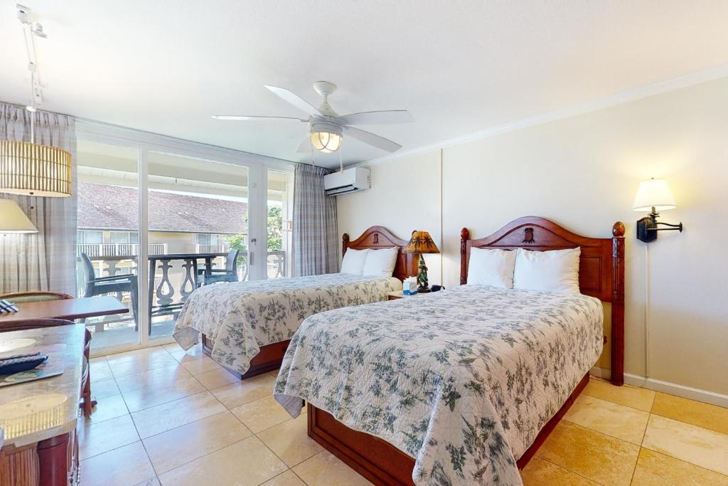 a bedroom with two beds and a balcony at Islander on the Beach 315 in Kapaa