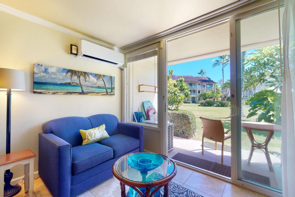 a living room with a blue couch and a glass table at Islander on the Beach 142 in Kapaa