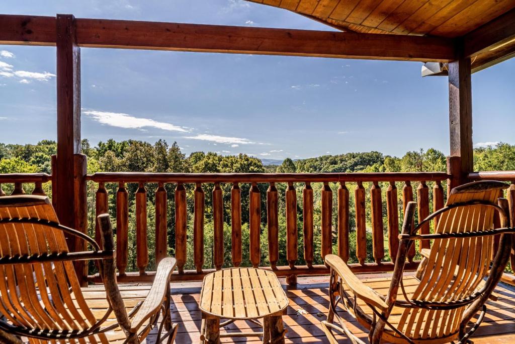 three chairs and a table on a deck with a view at The Gathering Place in Sevierville