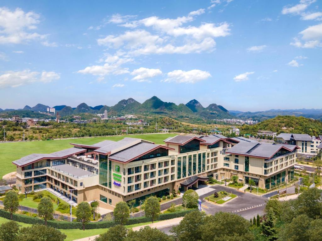 an aerial view of a building with mountains in the background at Holiday Inn Resort Guiyang Qingyan, an IHG Hotel in Guiyang
