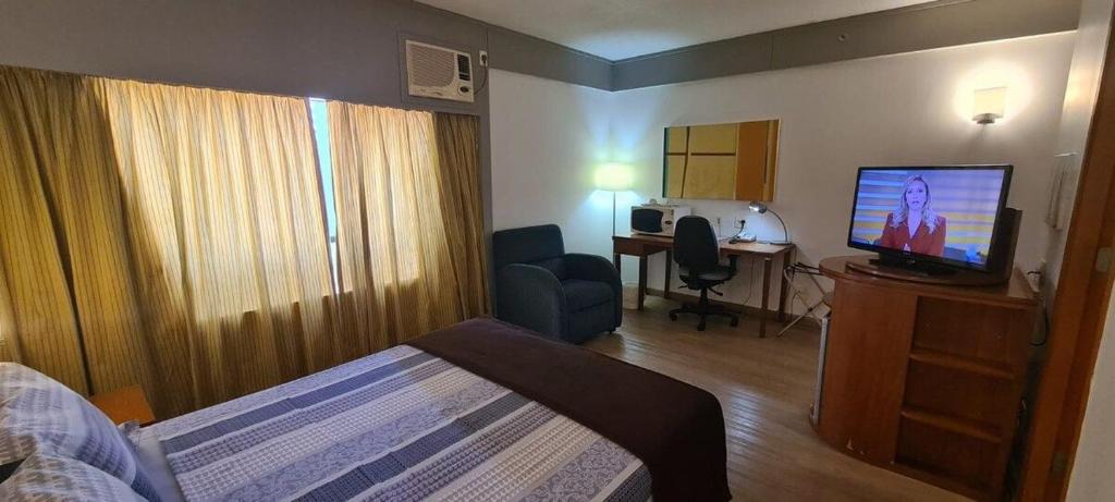 um quarto de hotel com uma cama, uma televisão e uma secretária em Flat Live & Lodge c/ vaga de garagem UH1003 em São Paulo