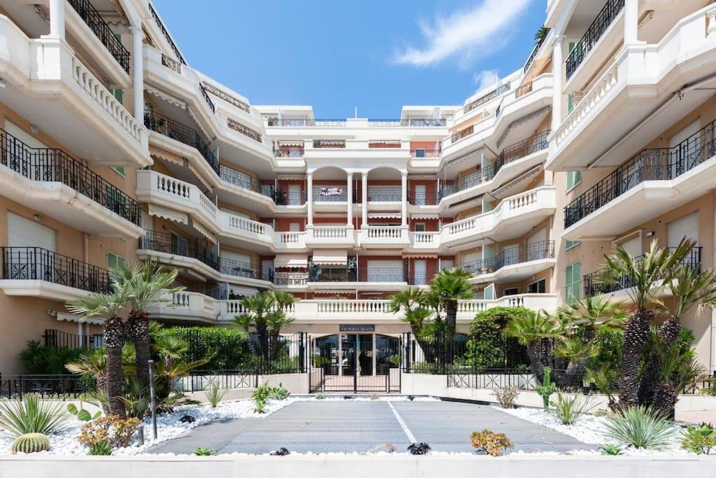 ein großes weißes Gebäude mit Palmen davor in der Unterkunft SUPERBE STUDIO AVEC TERRASSE EN FRONT DE MER in Menton