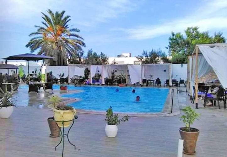 a large swimming pool with people in the water at Hotel Diar Meriam in Sousse