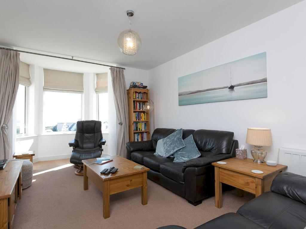 a living room with a black leather couch and a table at Pass the Keys Spectacular Sea View Apartment with free Parking in Trearddur