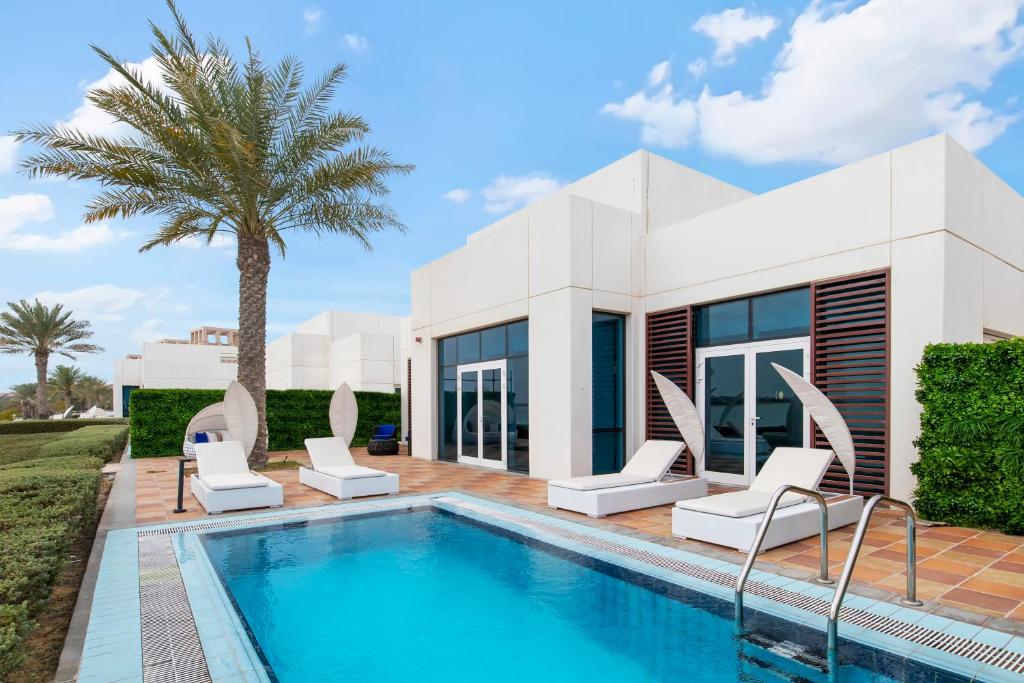 a villa with a swimming pool and a house at FAM Living - Sarai Beach Villas - Palm Jumeirah - Families Only in Dubai