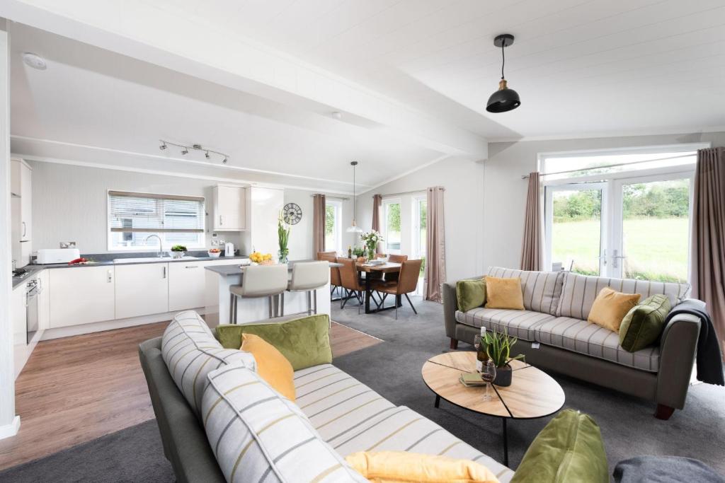 ein Wohnzimmer mit 2 Sofas und einer Küche in der Unterkunft Daisy Lodge, 6 Roadford Lake Lodges in Lifton