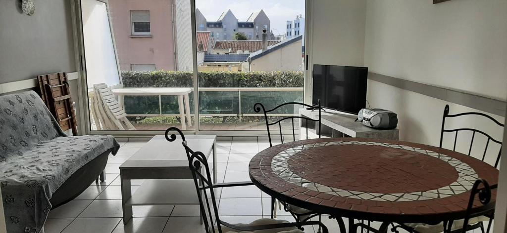 - un salon avec une table, des chaises et une grande fenêtre dans l'établissement L'Opale, à Berck-sur-Mer