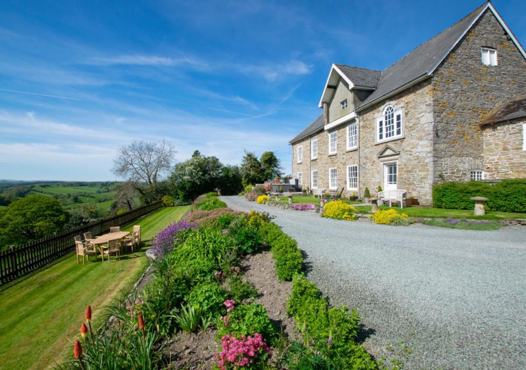 una gran casa de piedra con un jardín delante de ella en Trefnant Hall, en Welshpool