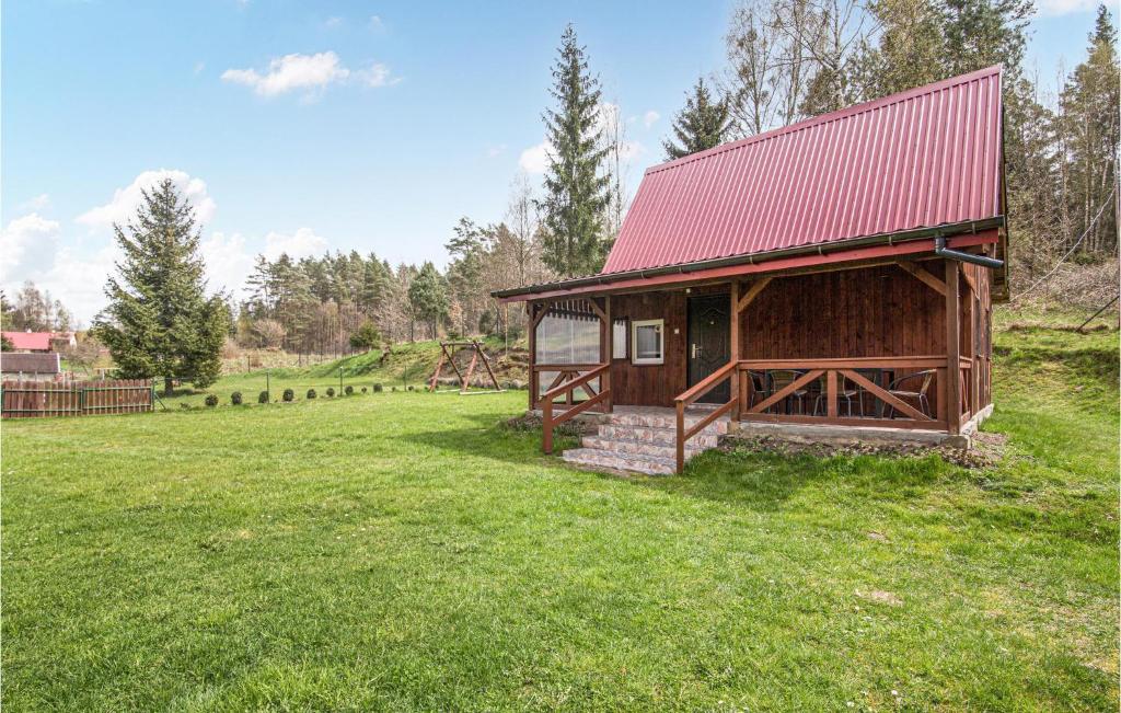 a small cabin with a red roof in a field at Gorgeous Home In Jedwabno With Kitchen in Jedwabno