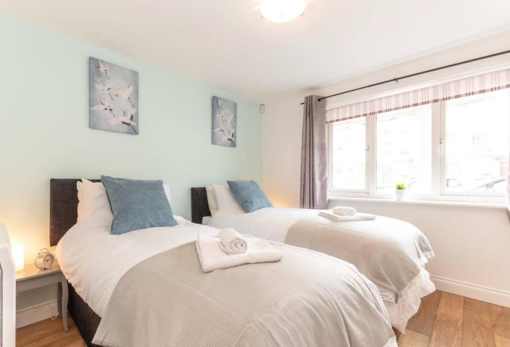two beds in a room with a window at Citrine - 2 Bed Apartment With Parking in Reading