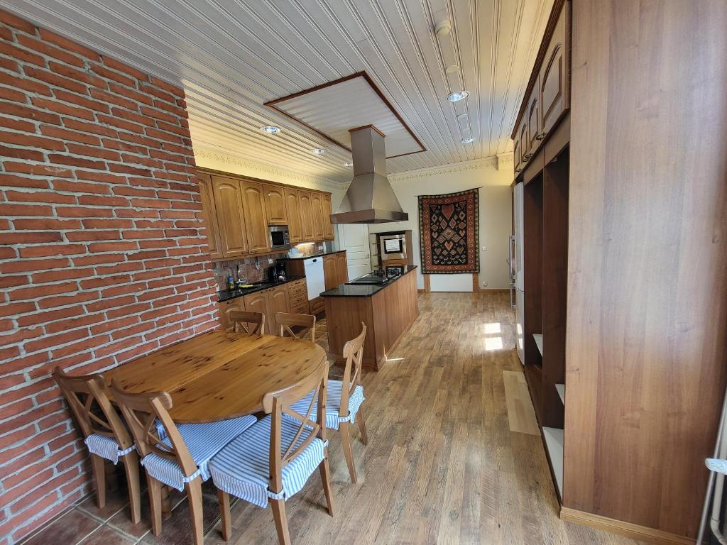 a kitchen with a wooden table and a brick wall at Kirstulan Kartanon päärakennuksessa sijaitseva hieno huoneisto in Hämeenlinna