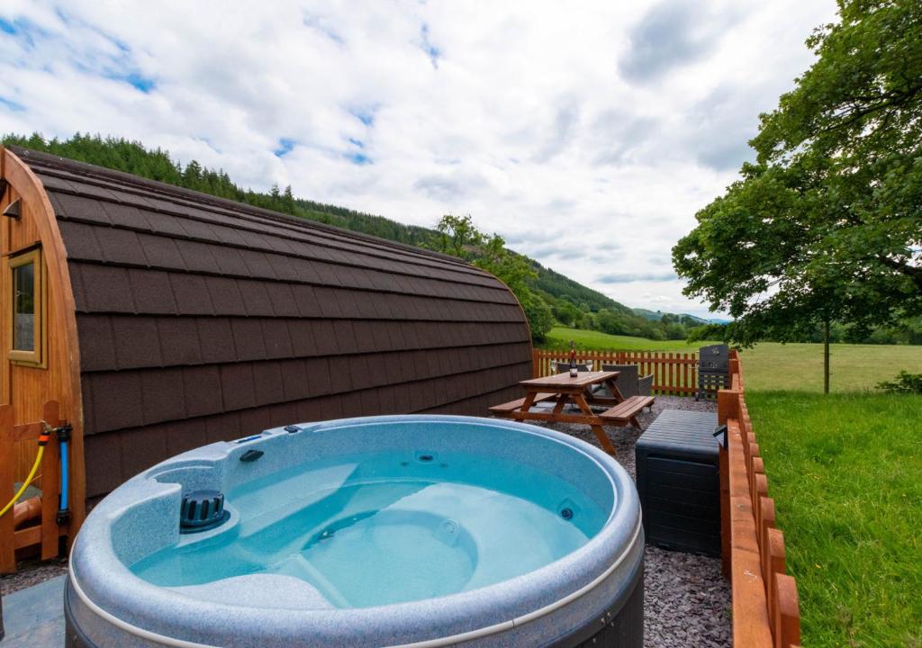a hot tub in a yard next to a building at Caban Clyd in Machynlleth