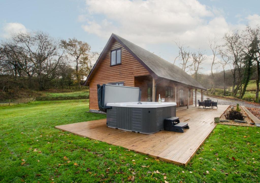 a hot tub on a deck next to a house at Nant y Llyn in Bala