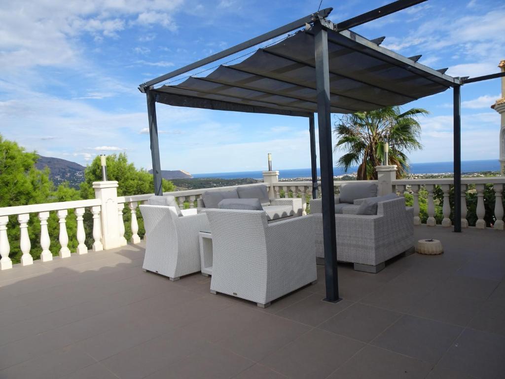 a gazebo with white furniture on a balcony at Villa Santorini Costa Blanca in La Nucía