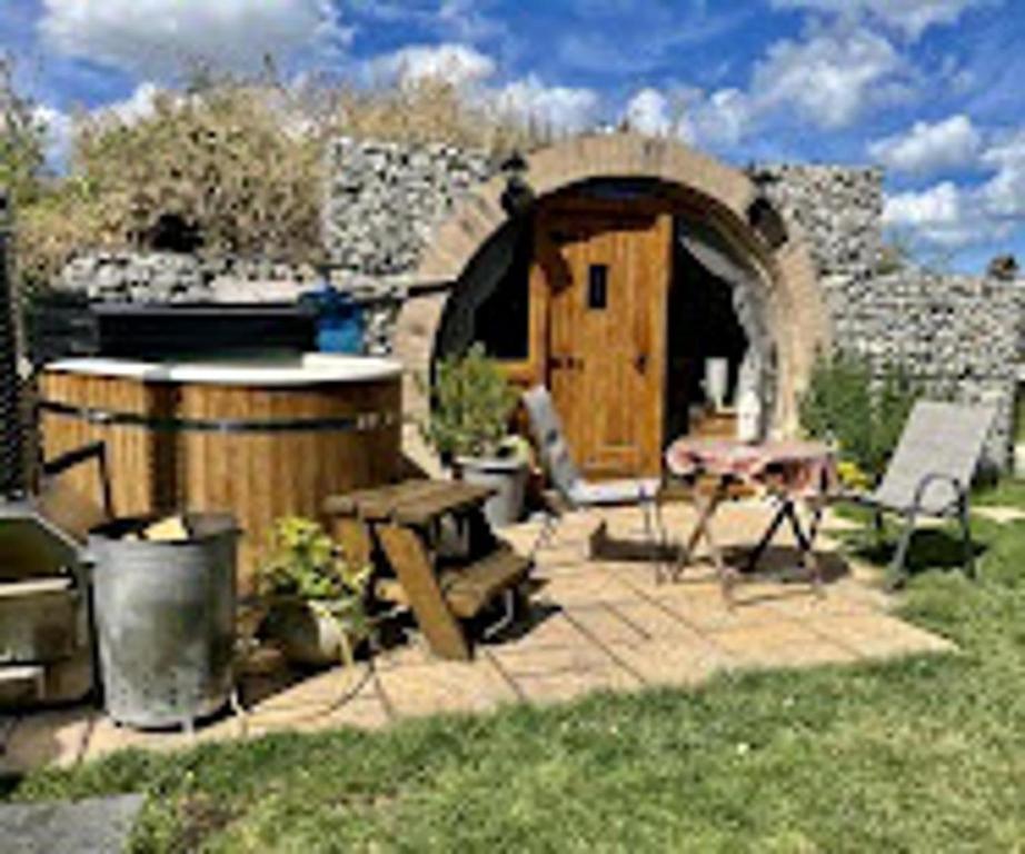 a backyard with a barrel and a table and a building at Romantic escape luxury Hobbit house with Hot tub! in Sheerness