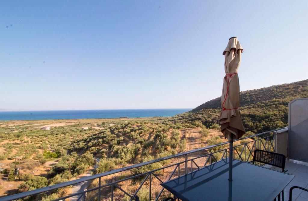 a balcony with an umbrella and the ocean in the background at Valtaki Holiday Home in Selinitsa
