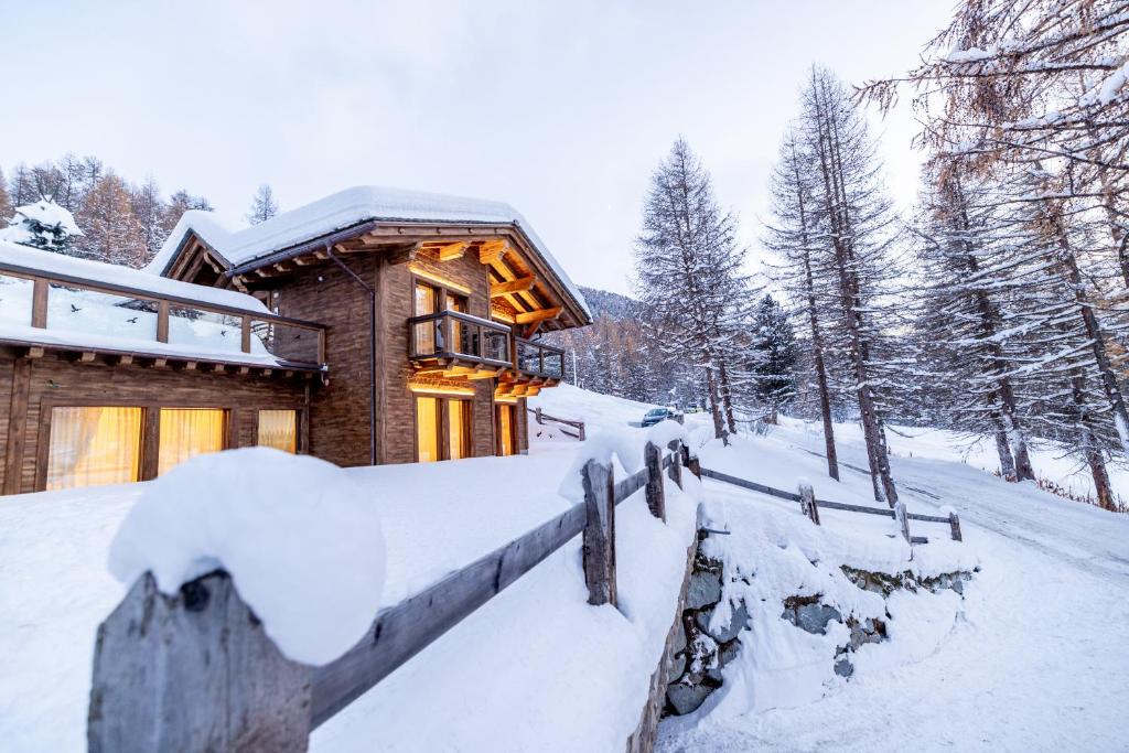 a log cabin in the snow with a fence at Chalet Imbosc'chè in Livigno