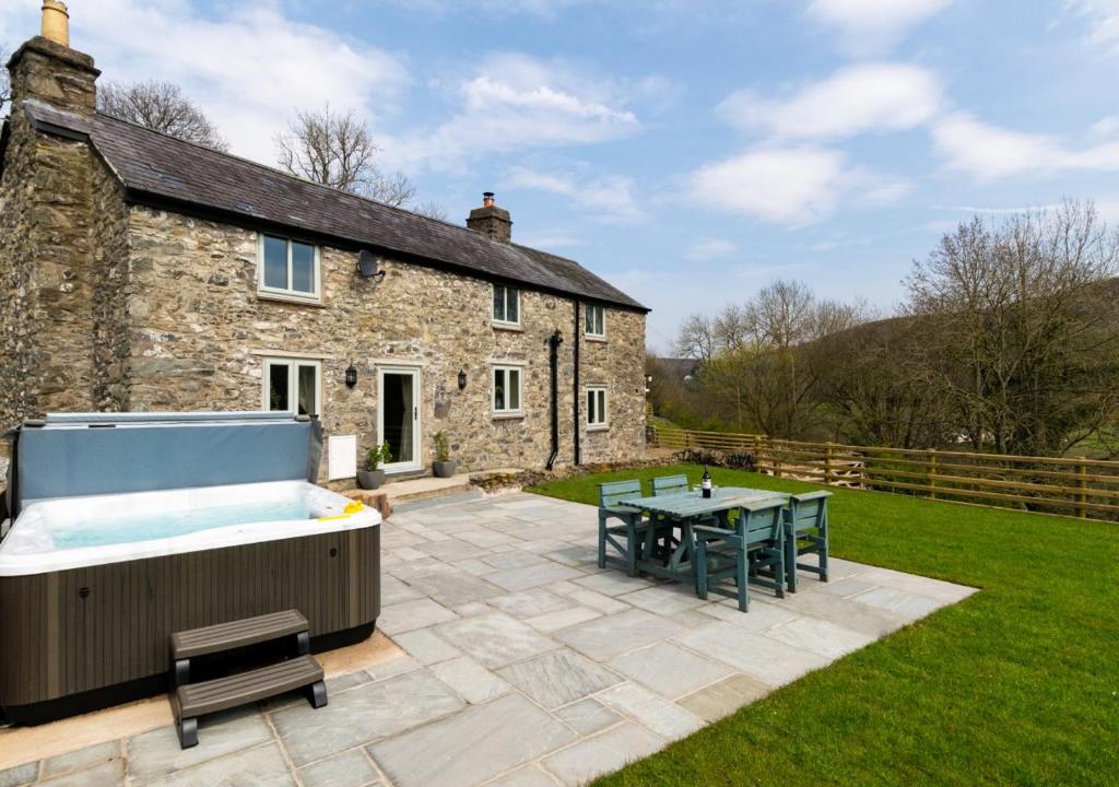 a garden with a hot tub and a table and a house at Ty Isa in Llanfair Talhaiarn