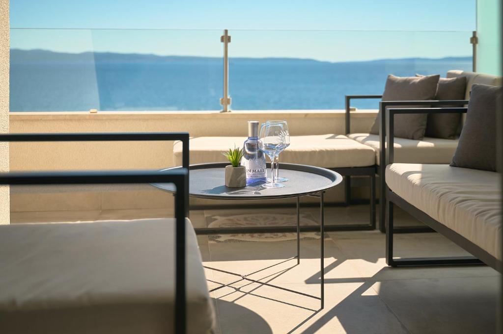 a table with two wine glasses on a balcony at Klara Beach Apartment in Split