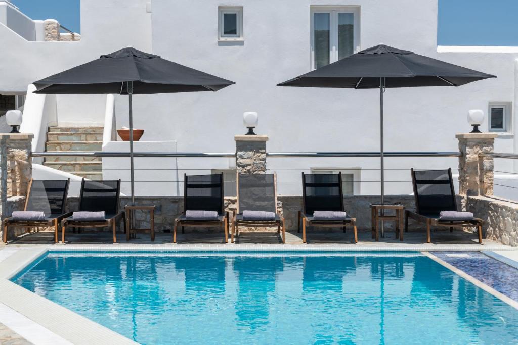 a pool with chairs and umbrellas on a building at Paliomylos Spa Hotel in Naousa