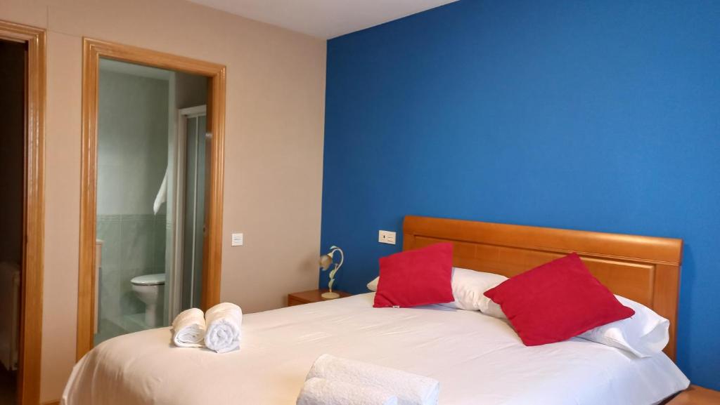 a blue room with a bed with red pillows at Corazón de Lemos in Monforte de Lemos