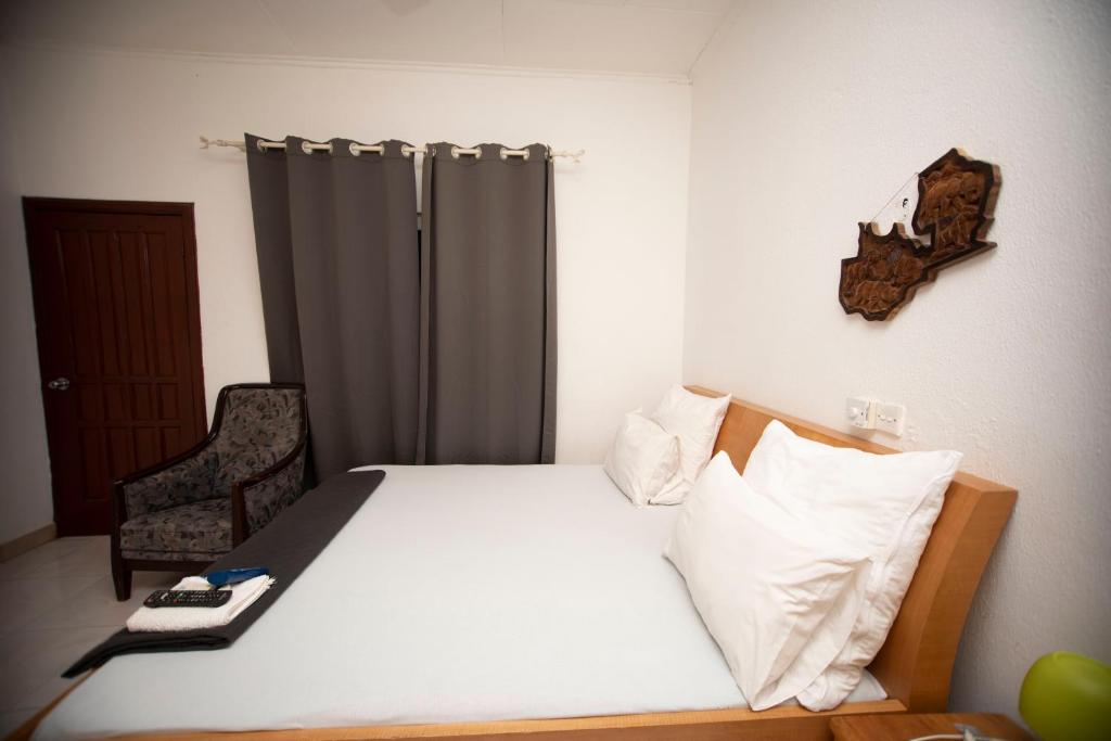 Marysin Guest house في آكرا: غرفة نوم بسرير وكرسي في غرفة