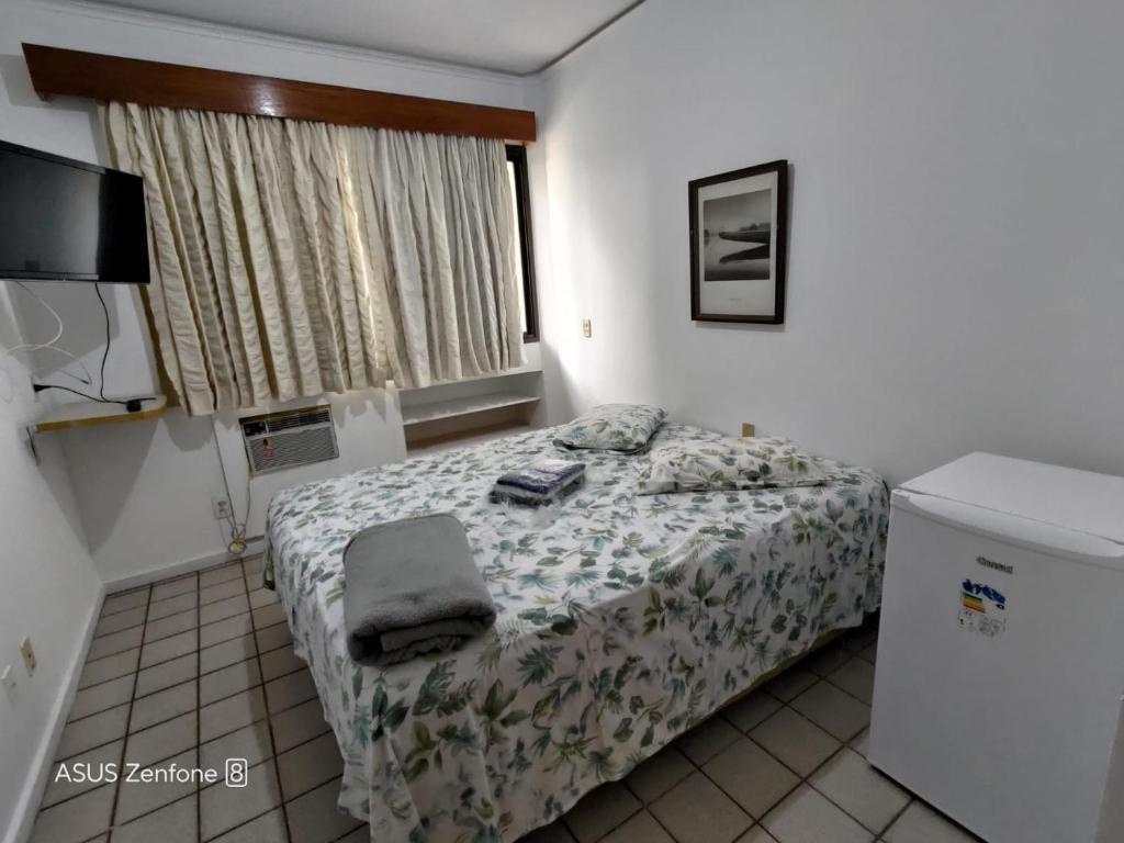 - une petite chambre avec un lit et une fenêtre dans l'établissement Flat Aconchegante na Orla de Camburi, à Vitória