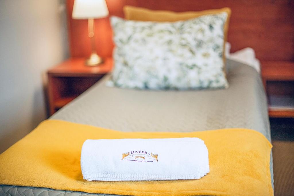 a hotel room with a white towel on a bed at Žuvėdra in Ignalina