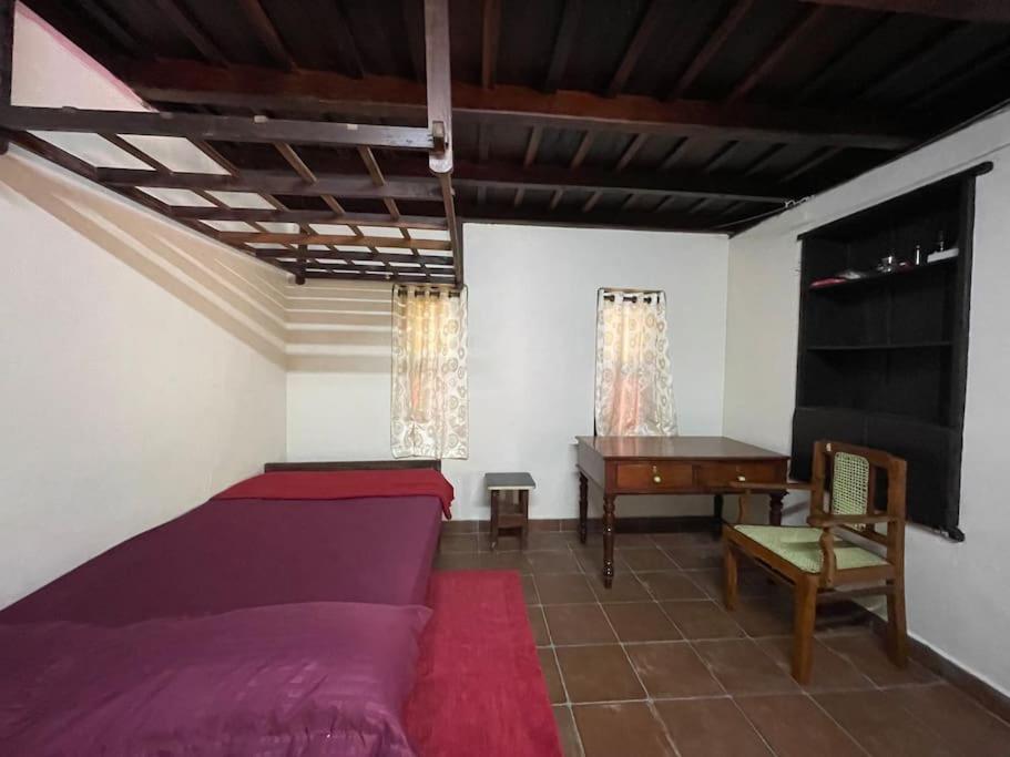 een slaapkamer met een bed en een bureau. bij Deesha Homes in Wayanad