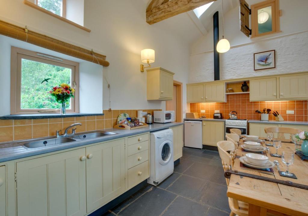 a kitchen with a sink and a dishwasher and a table at Stabal Pant y Lludw in Machynlleth