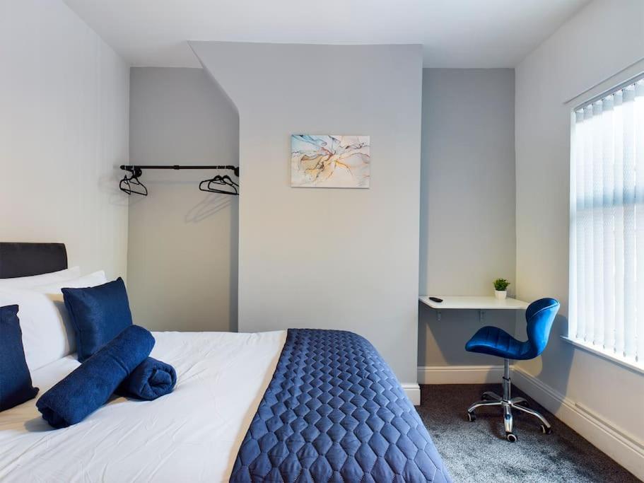 a bedroom with a bed with blue pillows and a chair at Whitmore House By RMR Accommodations - Newly Refurbed - Modern - Parking - Central in Etruria