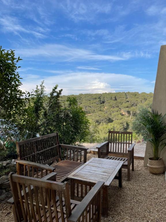 dois bancos de madeira e uma mesa de madeira com vista em Rez de Jardin en pleine nature em Ventabren