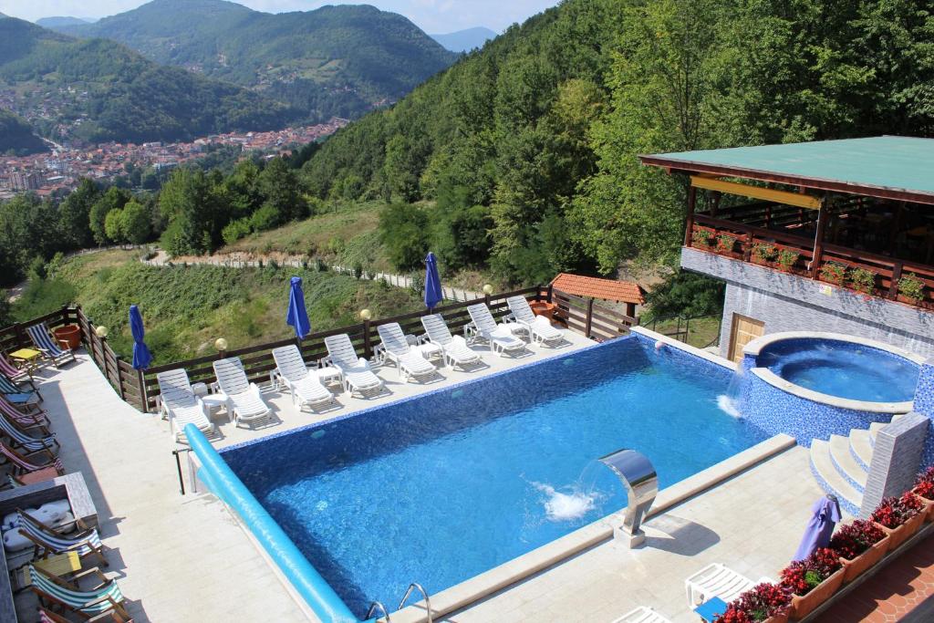 a swimming pool with chairs and a view of a mountain at "Naše Brdo" - Ivanjica in Ivanjica