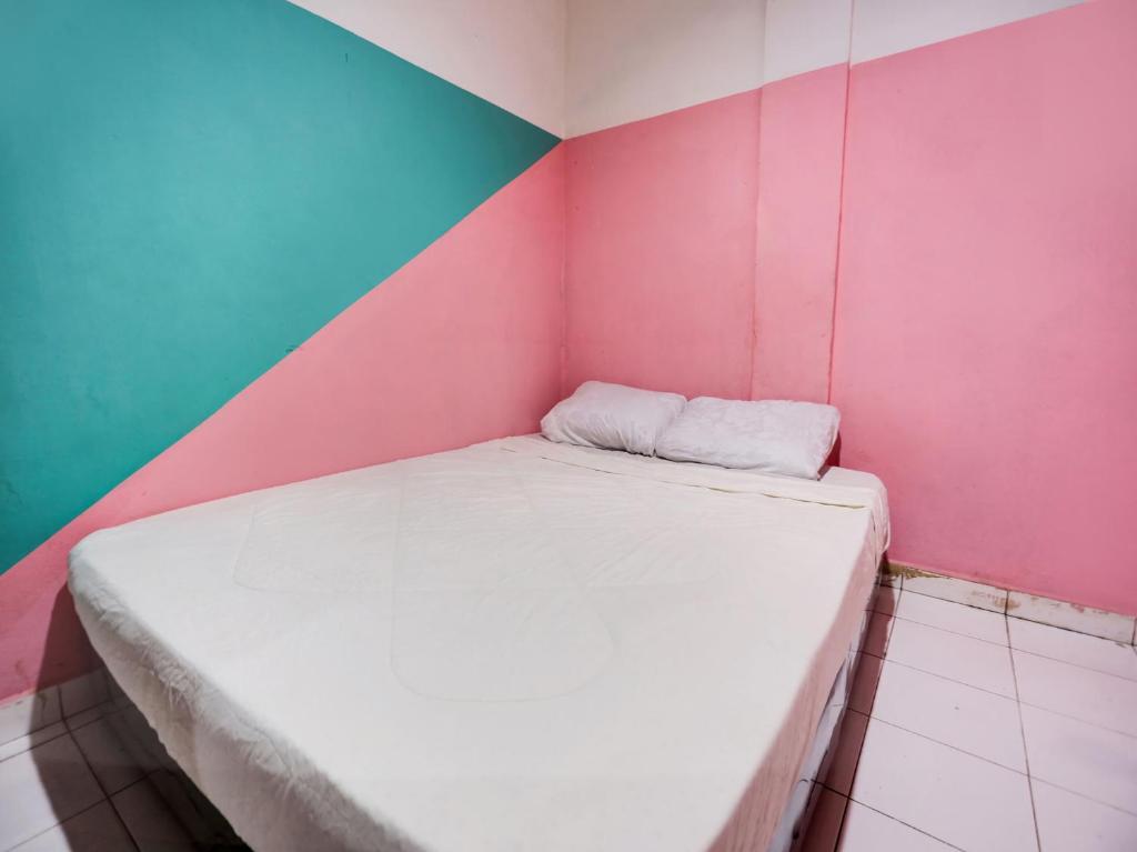 a small bed in a room with a colorful wall at SPOT ON 91781 Solo Baru Homestay Syariah in Jodoh